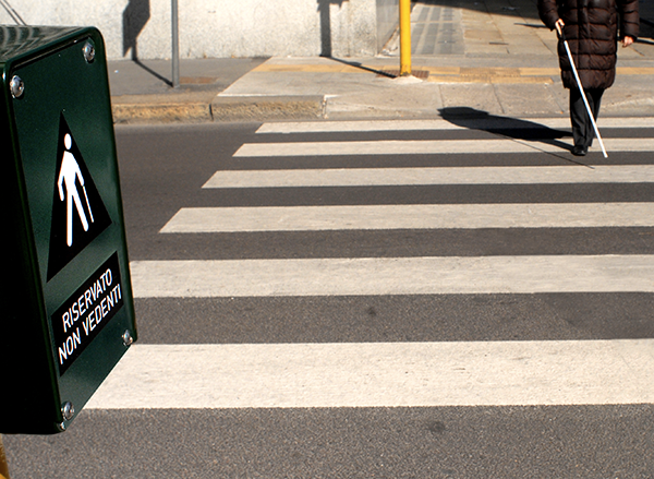 Attraversamento pedonale di un non vedente con pulsante sul semaforo avente scritta riservato non vedenti